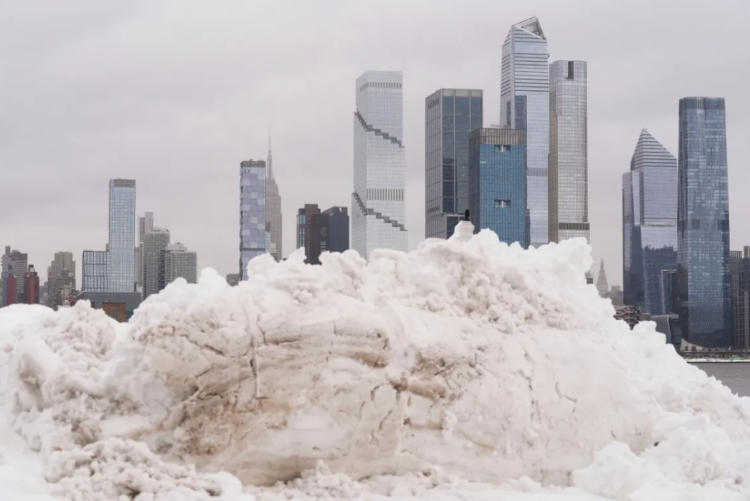 न्यूयॉर्क शहर की स्काईलाइन पर भारी बर्फ के ढेर, मैनहट्टन के पीछे skyscrapers बर्फ से ढके – 2026 snowstorm का खूबसूरत लेकिन खतरनाक नजारा। new york flights cancelled