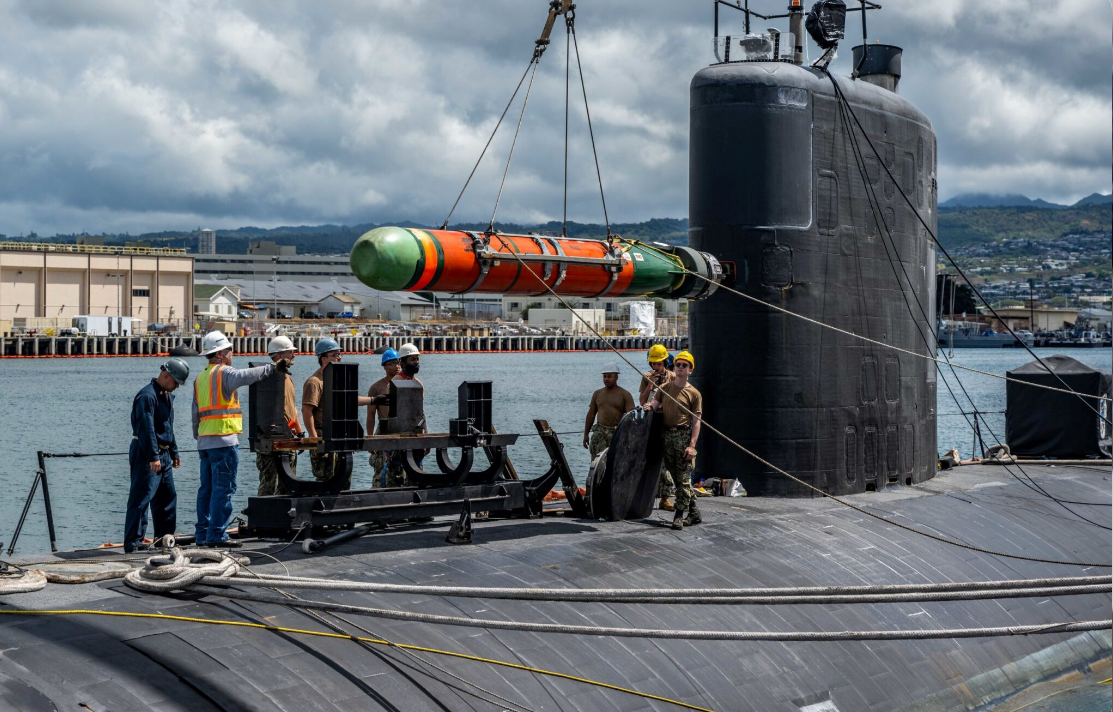 US नेवी क्रू द्वारा Mark 48 टॉरपीडो को सबमरीन में लोड करते हुए। IRIS Dena