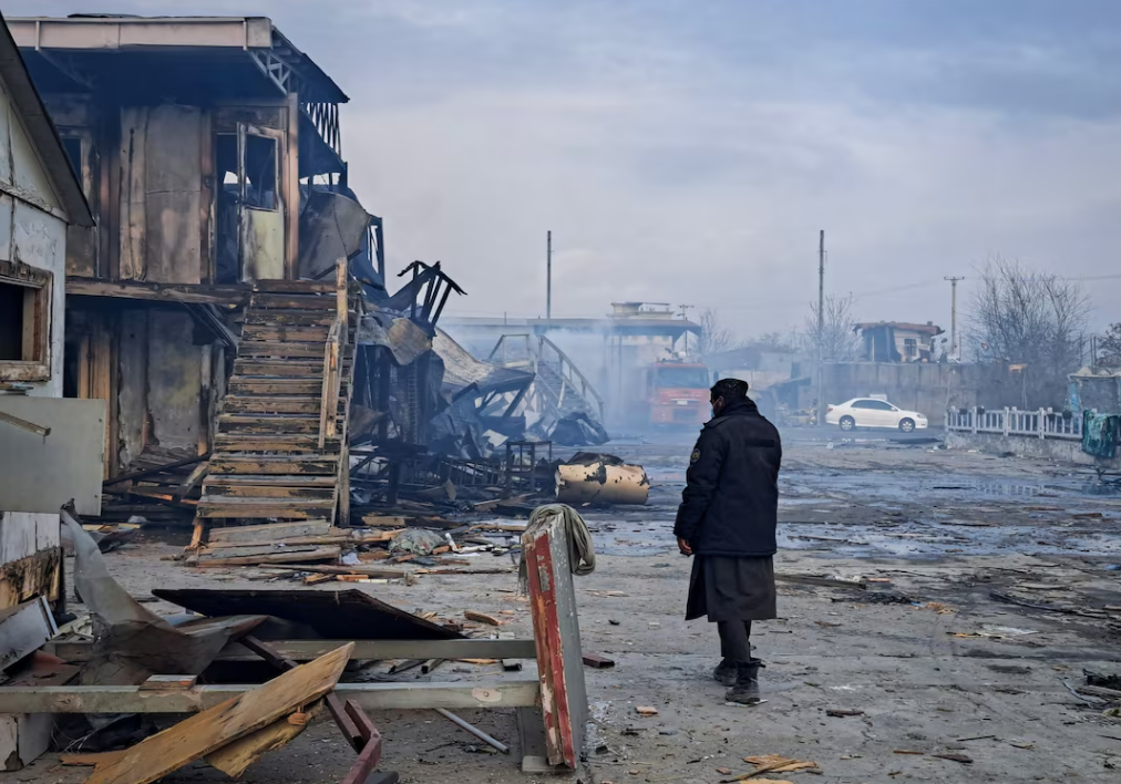 हमले के बाद Kabul Hospital के मलबे में खड़ा एक अफगान व्यक्ति – धुंध और धुएं के बीच तबाह इमारतें और जलती बिल्डिंग्स, घटना की मार्मिक तस्वीर।