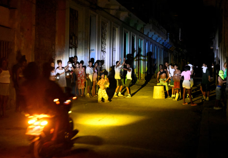 Cuba Energy Crisis 2026 में हवाना की रात, ब्लैकआउट के दौरान सड़क पर लोग टॉर्च और लाइट जलाकर इकट्ठा होकर बात करते हुए